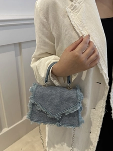 Chic light blue denim crossbody bag with fringe trim and silver chain shoulder strap