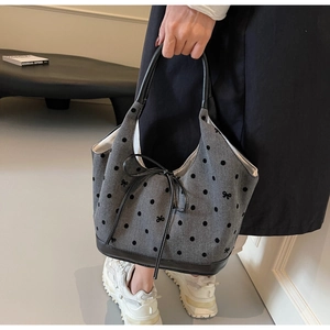 Nahaufnahme der grauen gepunkteten Canvas-Tasche mit schwarzer Schleife und Ledergriffen