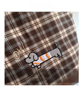 Close-up of a brown plaid tote bag with detailed embroidery of a dachshund and text OH!