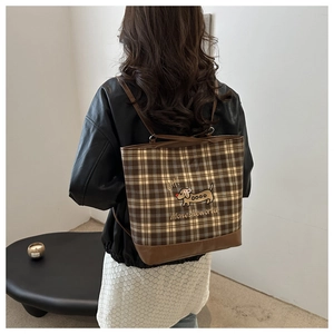 Detail of dachshund print on coffee plaid tote bag with leather strap shown on shoulder
