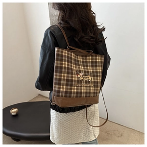 Detail of vintage brown plaid tote with dachshund embroidery and leather strap textures