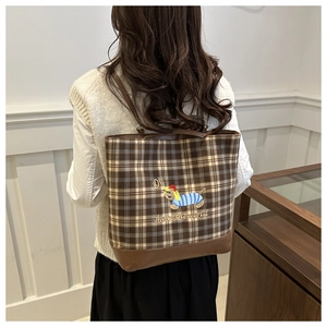 Plaid vintage tote bag detail showing cartoon dog embroidery and soft brown leather base