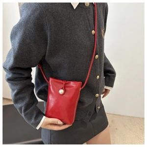 Vue détaillée du mini sac rouge pour téléphone avec bouton perle et fine bandoulière