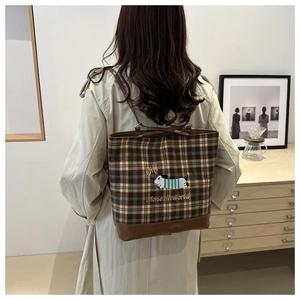 Macro detail of brown checkered tote bag featuring cute dachshund embroidery and leather base