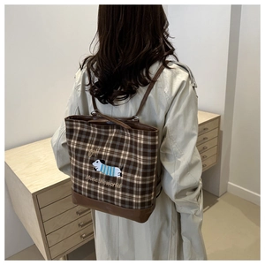 Brown plaid tote bag with cute dog embroidery shown on model back in a cozy room