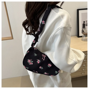 Detailed view of the knotted wide strap on a floral printed black underarm shoulder bag
