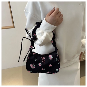 Detail of floral underarm bag featuring pink rose patterns and pleated handle with bow