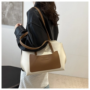 Détail du sac cabas bicolore porté à l'épaule par un mannequin en veste de cuir noir