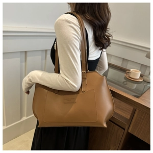 Detail view of large brown leather tote bag with adjustable shoulder strap and pocket