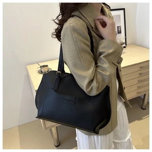 Détail du sac cabas en cuir noir avec poche avant et logo gravé mode élégant