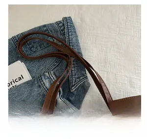 Detailed view of brown tote bag with white plush patchwork and slim handle on denim cloth
