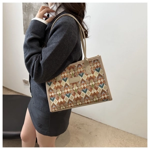 Vista laterale di una borsa tote vintage in tela con motivi geometrici su una modella