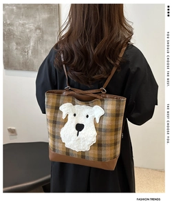 Detail of plaid tote bag featuring a cute white dog patch and premium brown leather straps