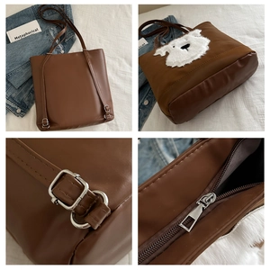 Detail of a brown tote bag featuring a cute white plush dog motif and metal zipper