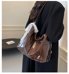 Detail of dark brown patent leather tote with H-stitching and lace bow accent