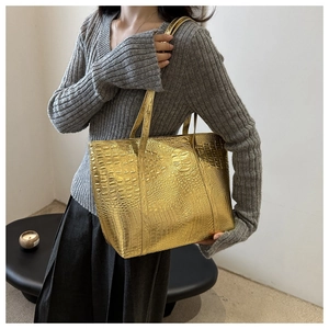 Détail du sac cabas doré avec motif crocodile gaufré et finition métallique brillante