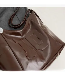 Detail of dark brown glossy PU leather tote bag featuring a large number 10 design element