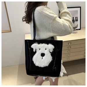 Shoulder shot of black glossy tote bag with white plush dog patch and slim strap