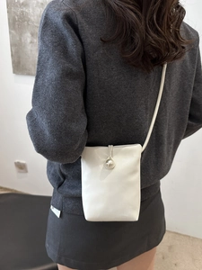 Minimalist white mini shoulder bag with pearl clasp decoration worn by a model