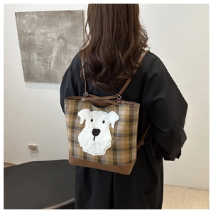 Détail du sac à dos à carreaux en laine avec écusson chien en peluche et base en cuir