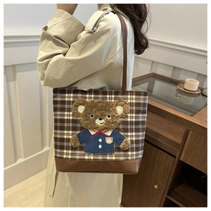 Detail of retro plaid tote bag with plush bear patch and reinforced leather base
