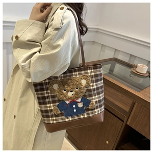 Détail du sac cabas à carreaux avec écusson ours en peluche et base en cuir marron