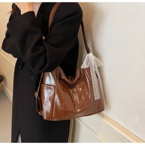 Detail of brown vintage leather tote bag with number ten patch and white lace bow