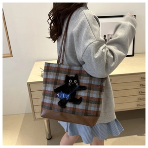 Détail d'un sac cabas à carreaux avec broderie chat et base en cuir marron