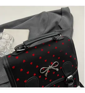 Detail of black canvas handbag with red heart patterns and silver metal bow ornament