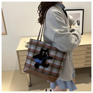 Detailed side view of large plaid tote bag with cat embroidery worn by a model