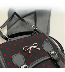 Macro shot of black backpack with red heart patterns and silver bow buckle detail