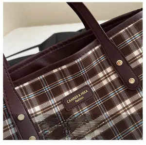 Detail of checkered tote bag featuring leather straps and embossed fashion logo brand