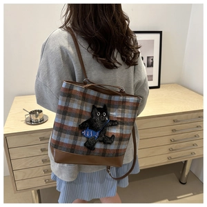Detail of a large plaid tote bag featuring a cute black cat and fish embroidery patch