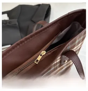 Detailed view of the smooth gold zipper and brown checkered texture on this tote bag
