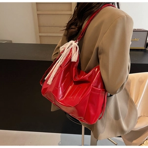 Detail of red oversized hobo tote bag with delicate white lace bow and side pocket