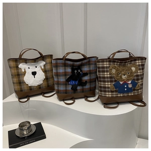 Close-up of plaid tote bags with cute cartoon animal patches on minimalist display