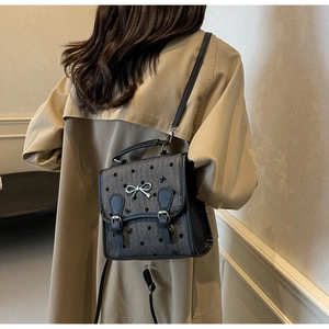 Detail of grey polka dot crossbody bag with silver bow accent and black strap