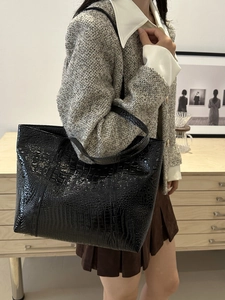 Grand sac cabas noir en cuir verni avec motif crocodile porté par un mannequin