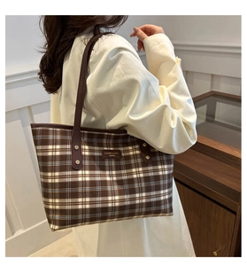 Detail of vintage plaid tote bag with brown leather trim and metallic rivets