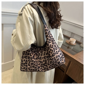Close-up of leopard print tote bag with wide black strap on female model shoulder