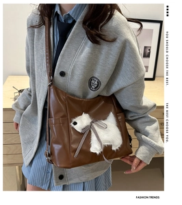 Brown faux leather shoulder bag featuring a white plush puppy patch with a bow detail