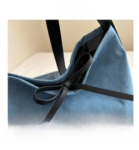 Detailed close-up of the blue denim bucket bag featuring a chic black leather bow accent