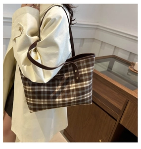 Detail showing vintage plaid tote bag with brown leather straps and woven brand label