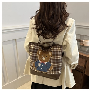 Dettaglio della borsa tote a quadri marrone con patch orsetto e cinturini in pelle