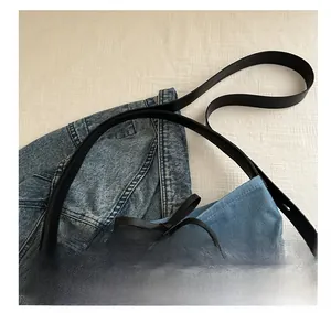 Detail of adjustable black leather strap and blue denim canvas bucket bag with bow