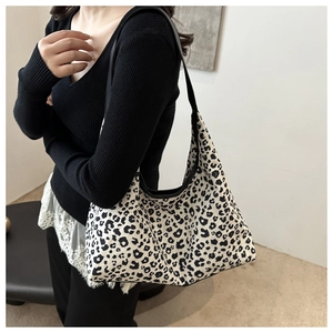 Detail shot of black and white leopard print canvas hobo bag worn by a model