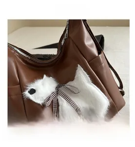 Detailansicht der braunen PU-Ledertasche mit weißem Plüschhund-Patch und Schleife