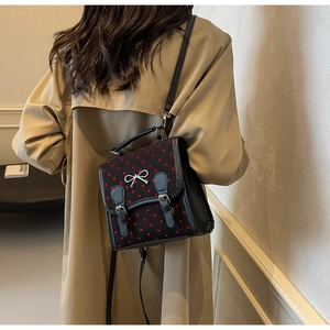 Detail of black balletcore backpack with red heart patterns and silver bow buckle