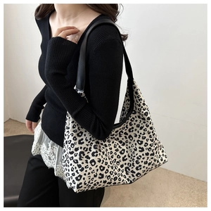 Detail of large leopard print canvas tote bag featuring black wide strap and zipper closure