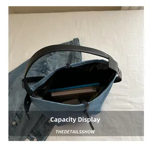 Detail view of denim bucket bag capacity showing an iPad and books inside with wide strap